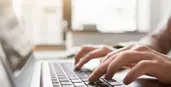 "Hands typing on a laptop"
